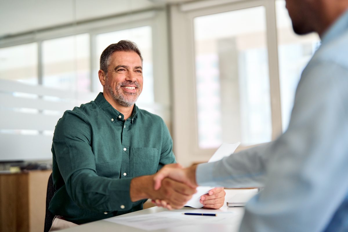 Smiling man shaking hand with his boss after interview and discussing personality test